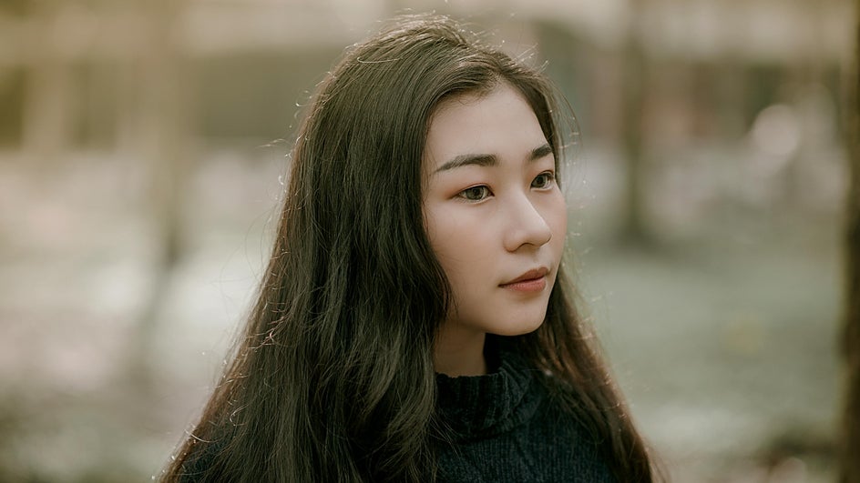 female portrait long black hair and black sweater on outdoor background