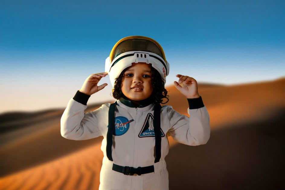 little boy in astronaut costume with sand dune space background