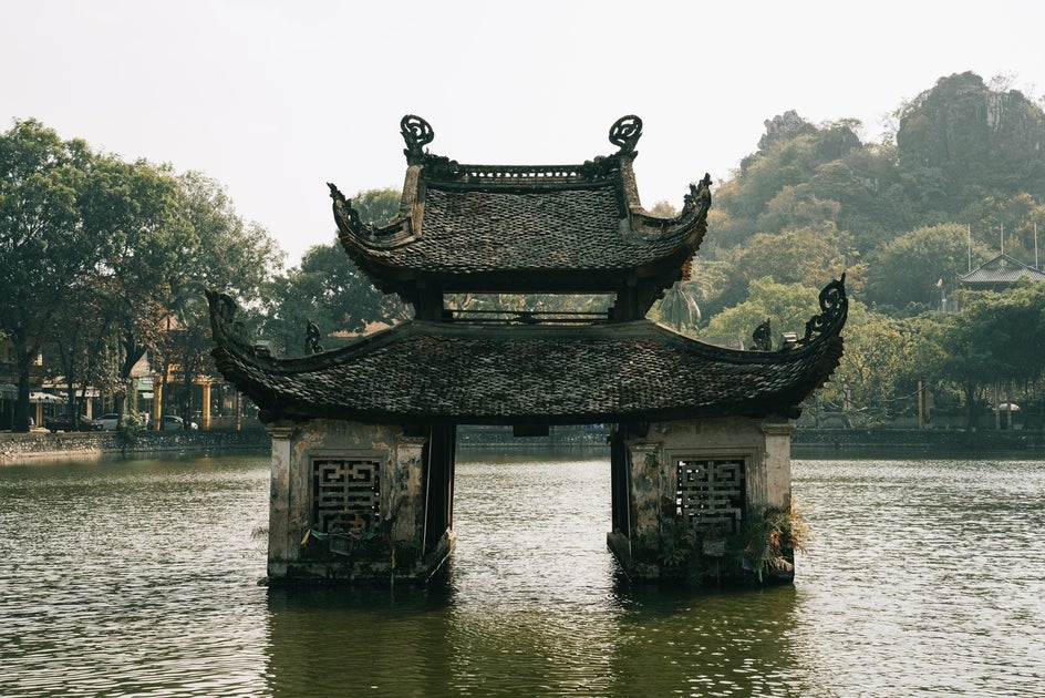 Before: A tranquil scene of a traditional shrine gate standing in calm water.