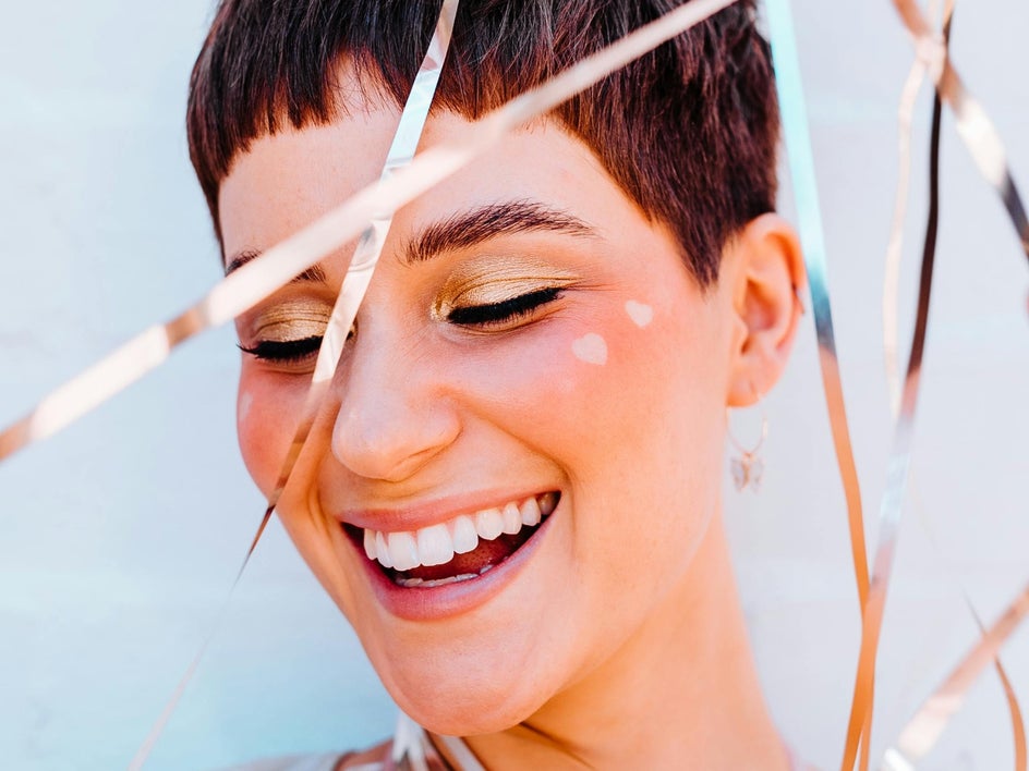 close up portrait of woman smiling with streamers and heart eye makeup