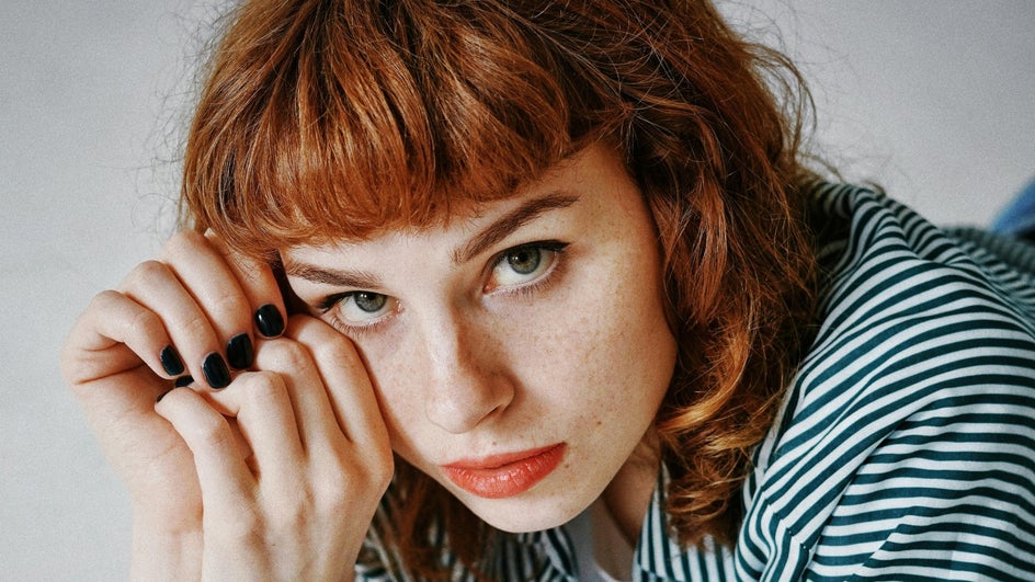 close up of woman with freckles, red hair, and bangs